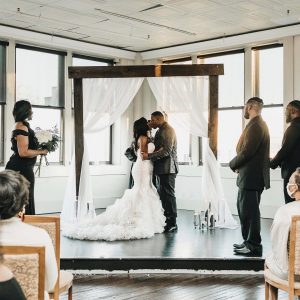 couple kissing in front of large, beautiful windows at The Martinsborough in Greenville, NC